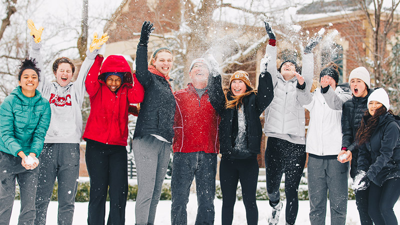 Ten people lined up throwing snow in the air